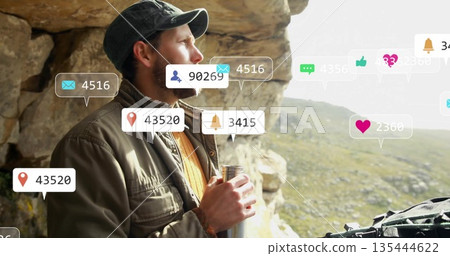 Gazing hiker wearing cap, field jacket at rocky overlook, holding flask and digital overlay icons Gazing hiker wearing cap, field jacket at rocky overlook, holding flask and digital overlay icons 135444622
