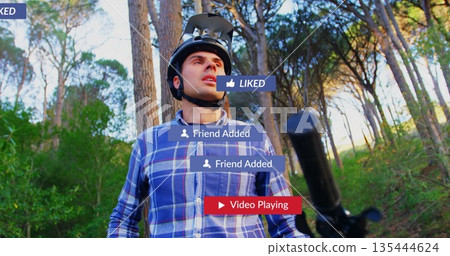 Standing man wearing bicycle helmet and blue plaid shirt on wooded trail, with social media icons Standing man wearing bicycle helmet and blue plaid shirt on wooded trail, with social media icons 135444624