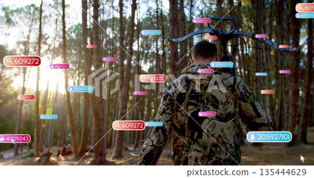 Walking hunter in camouflage with crossbow at dusk pine forest, with data tags and numeric overlays 135444629