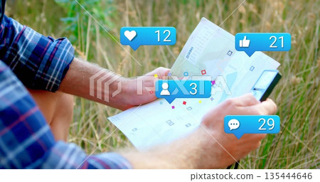 Man in checkered shirt and shorts examining clipboard map in grassy field with social media icons 135444646