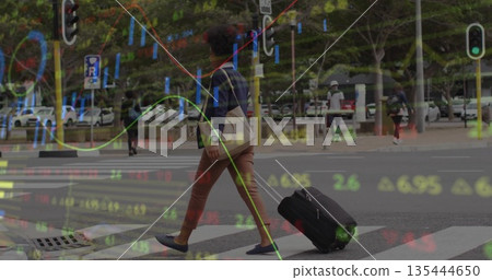 Crossing woman pulling suitcase and carrying tote bag on urban zebra crossing, stock market overlay 135444650