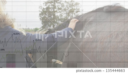 Reaching woman wearing puffer coat stroking brown horse in pasture, with data charts, copy space 135444663