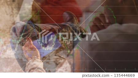 Asian man analyzing stock charts on tablet sitting on sofa in living room, with cushion, blanket Asian man analyzing stock charts on tablet sitting on sofa in living room, with cushion, blanket 135444669
