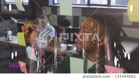 Sketching hoodie-clad man drawing diagrams on glass board in office, with sticky notes, copy space 135444682
