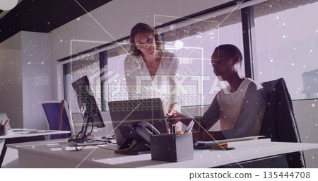 Leaning women wearing business attire pointing at laptop screen and typing in office with documents 135444708