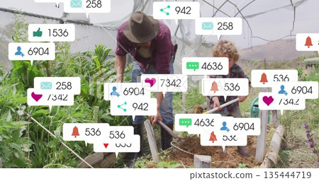 Working parent-child duo shoveling soil at raised bed inside greenhouse, with feedback icons 135444719