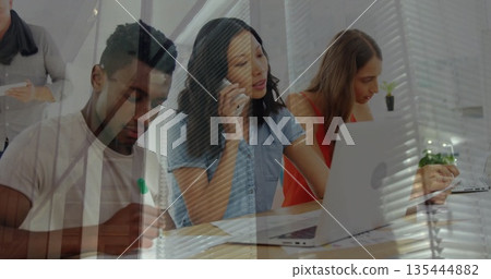Collaborating colleagues gathering around conference table, using laptop smartphone notepad marker Collaborating colleagues gathering around conference table, using laptop smartphone notepad marker 135444882