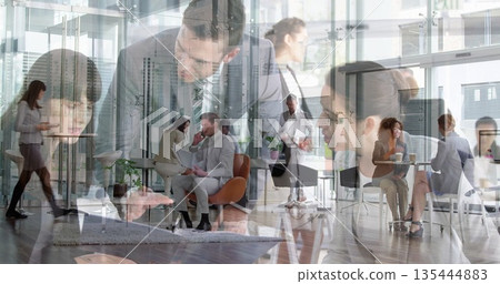 Chatting man in suit and woman in blazer sitting in office lounge, with orange chairs 135444883