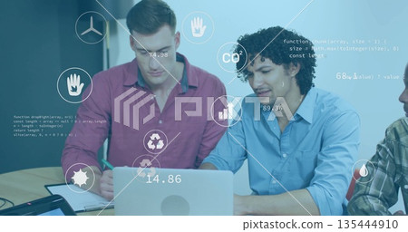 Collaborating coworkers writing notes and typing on laptop at meeting table, with data icons Collaborating coworkers writing notes and typing on laptop at meeting table, with data icons 135444910