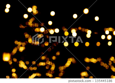 Golden festive lights blurred in abstract bokeh effect against dark background, creating a warm and 135445186