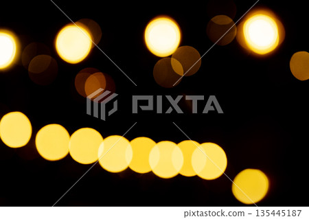 Golden yellow bokeh lights glowing softly against a dark background, creating a dreamy festive Golden yellow bokeh lights glowing softly against a dark background, creating a dreamy festive 135445187