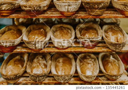 Baking bread. Dough in proofing basket on wooden table with flour, cumin and wheat ears. Top view. Baking bread. Dough in proofing basket on wooden table with flour, cumin and wheat ears. Top view. 135445261