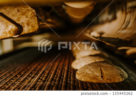 Fresh buns from the oven. Conveyor with bread. Baking bread. Workshop for production of bread. White bread in the oven. Hot buns. Confectionery. 135445262