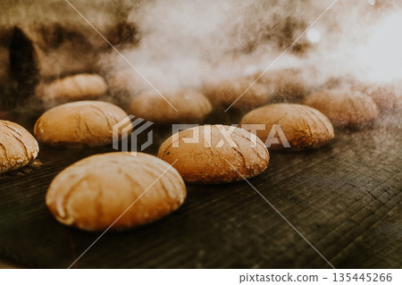 Fresh buns from the oven. Conveyor with bread. Baking bread. Workshop for production of bread. White bread in the oven. Hot buns. Confectionery. 135445266