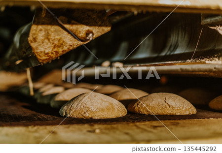 Fresh buns from the oven. Conveyor with bread. Baking bread. Workshop for production of bread. White bread in the oven. Hot buns. Confectionery. 135445292