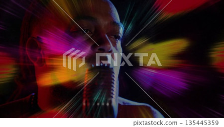 Singing man performing in dark studio space, with vintage-style microphone and colored light beams Singing man performing in dark studio space, with vintage-style microphone and colored light beams 135445359