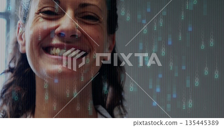 Smiling mid adult woman wearing white top displaying binary overlay in studio, with code streams 135445389