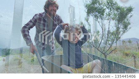 Guiding man wearing plaid shirt pushing green wheelbarrow on dirt track with boy and data overlay Guiding man wearing plaid shirt pushing green wheelbarrow on dirt track with boy and data overlay 135445406