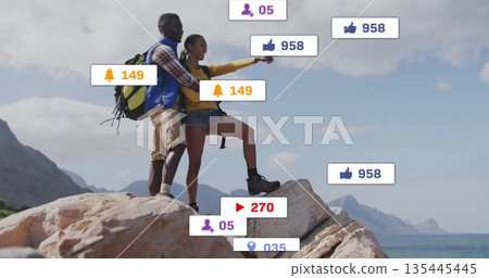 Pointing couple standing atop cliff overlooking ocean, with hiking backpacks, social media icons 135445445