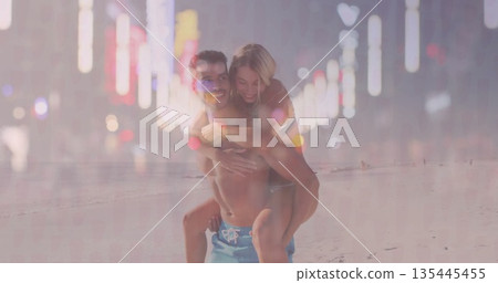 Walking Hispanic man carrying woman on back at sandy beach at dusk, with swim trunks, swimsuit Walking Hispanic man carrying woman on back at sandy beach at dusk, with swim trunks, swimsuit 135445455