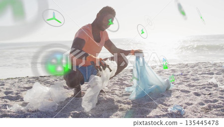 Squatting volunteer in pink shirt picking up plastic debris on sandy shoreline, with bright gloves Squatting volunteer in pink shirt picking up plastic debris on sandy shoreline, with bright gloves 135445478
