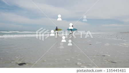 Two men in wetsuits walking through shallow water at beach, carrying lime green and teal surfboards Two men in wetsuits walking through shallow water at beach, carrying lime green and teal surfboards 135445481
