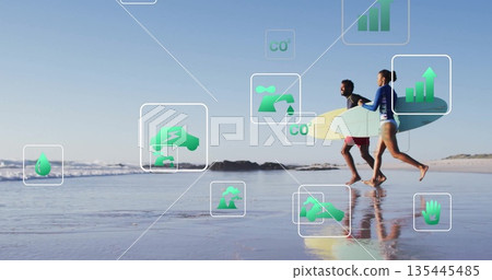 Running couple wearing rash guards carrying surfboard on beach with floating eco icons, copy space Running couple wearing rash guards carrying surfboard on beach with floating eco icons, copy space 135445485
