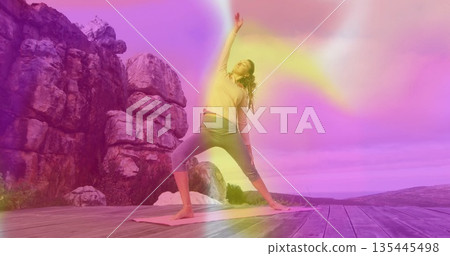 Stretching woman wearing sportswear reaching overhead on wooden platform against rock formation Stretching woman wearing sportswear reaching overhead on wooden platform against rock formation 135445498