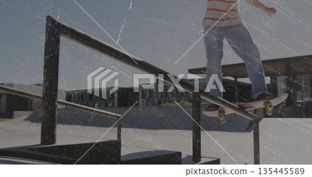 Grinding male skateboarder sliding along metal handrail in outdoor skate park, copy space Grinding male skateboarder sliding along metal handrail in outdoor skate park, copy space 135445589