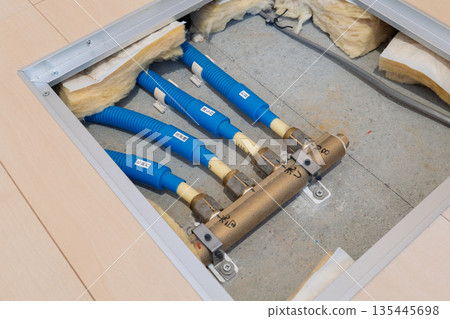 Water supply pipe header and piping visible from the underfloor inspection hatch in an apartment building Water supply pipe header and piping visible from the underfloor inspection hatch in an apartment building 135445698