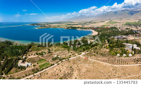 Serene landscape with mountains, water, and beach resort in Issyk-Kul lake 135445783