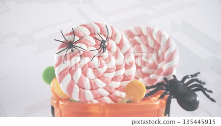 Spiders falling over in halloween pumpkin bucket filled with candies against 3d concentric shapes Spiders falling over in halloween pumpkin bucket filled with candies against 3d concentric shapes 135445915