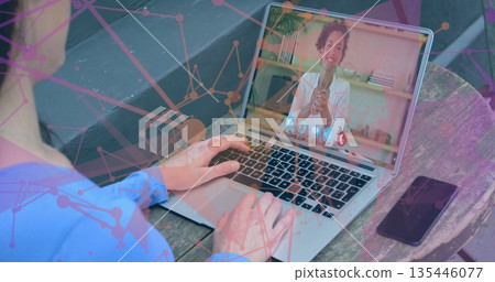 Typing man using silver laptop joining remote call on park bench, with smartphone network overlay 135446077