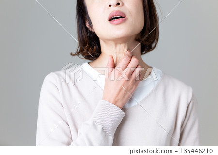 A middle-aged woman suffering while holding her throat 135446210
