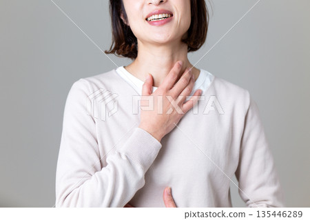 A middle-aged woman suffering while holding her throat 135446289