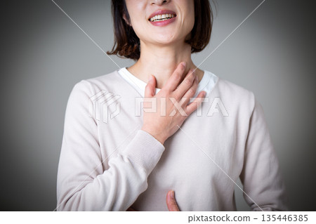 一位中年婦女痛苦地摀著喉嚨 一位中年婦女痛苦地摀著喉嚨 135446385