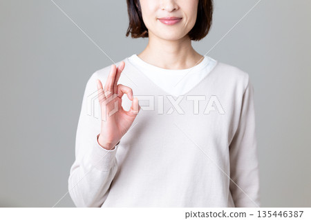 一位身著休閒裝的中年婦女比劃著圓圈手勢 135446387