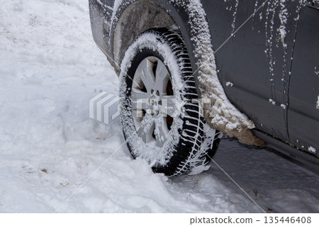 Road salt around the wheel arch of a snow covered car 135446408