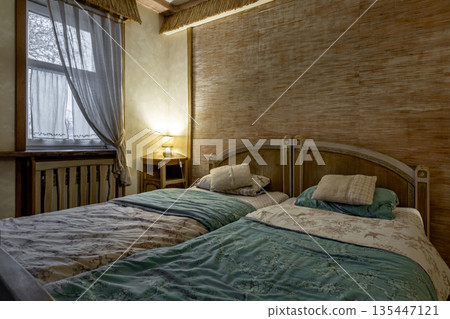 Cozy rustic bedroom interior with twin beds and warm lighting 135447121