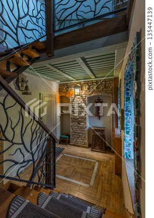 Rustic hallway interior with tree branch wrought iron stairs and brick wall 135447139