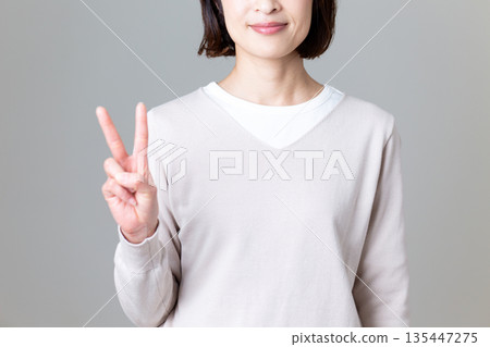 一位身著休閒服的中年婦女比出和平手勢 135447275