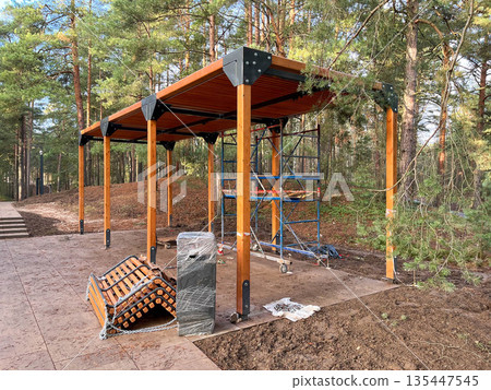 Construction of a wooden pavilion in a forested area during daylight Construction of a wooden pavilion in a forested area during daylight 135447545