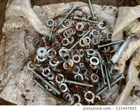 Scattered metal fasteners and hardware on a white tarp outdoors in autumn Scattered metal fasteners and hardware on a white tarp outdoors in autumn 135447605