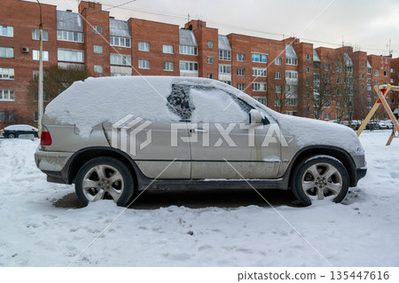 Snow covers parked car in residential area during winter season 135447616