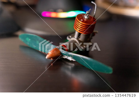 Small model engine with a propeller placed on a dark surface in a workshop setting Small model engine with a propeller placed on a dark surface in a workshop setting 135447619