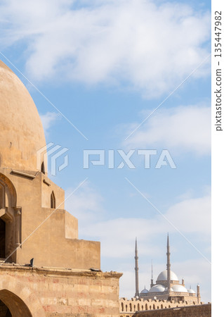 Ibn Tulun Mosque in Cairo features a large dome and intricate architectural details. The structure showcases Islamic design elements and historical significance. 135447982