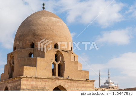 Ibn Tulun Mosque in Cairo features a large dome and intricate architectural details. The structure showcases Islamic design elements and historical significance. Ibn Tulun Mosque in Cairo features a large dome and intricate architectural details. The structure showcases Islamic design elements and historical significance. 135447983