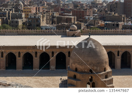 Ibn Tulun Mosque in Cairo features a large dome and intricate architectural details. The structure showcases Islamic design elements and historical significance. Ibn Tulun Mosque in Cairo features a large dome and intricate architectural details. The structure showcases Islamic design elements and historical significance. 135447987