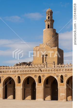 Ibn Tulun Mosque in Cairo. The mosque features a tall minaret and intricate architectural details. Blue sky visible in the background. Ibn Tulun Mosque in Cairo. The mosque features a tall minaret and intricate architectural details. Blue sky visible in the background. 135448059