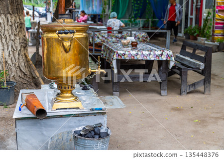 Brass samovar on outdoor cafe table with patterned tablecloth 135448376